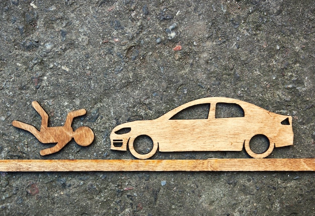 Jouet en bois petit homme et voiture sur fond de pierre. Accident de voiture concept avec l'homme