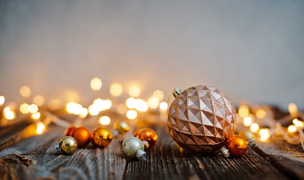 Jouet boule de sapin de Noël posé sur une table en bois contre un bokeh de lumières de Noël.