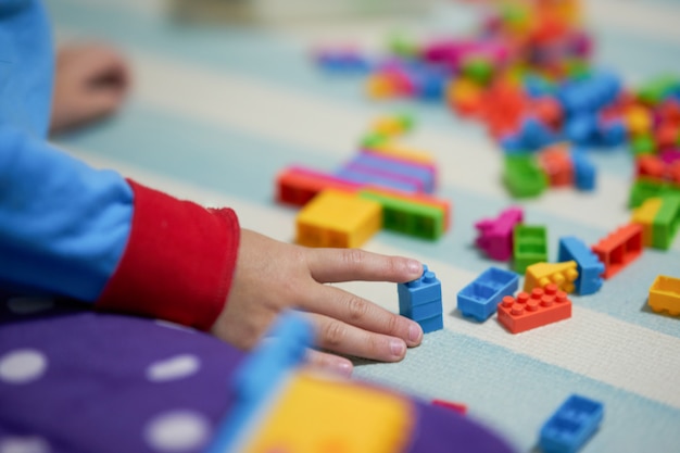 Jouet de briques colorées à la main d&#39;enfant sur le tapis pour jouer