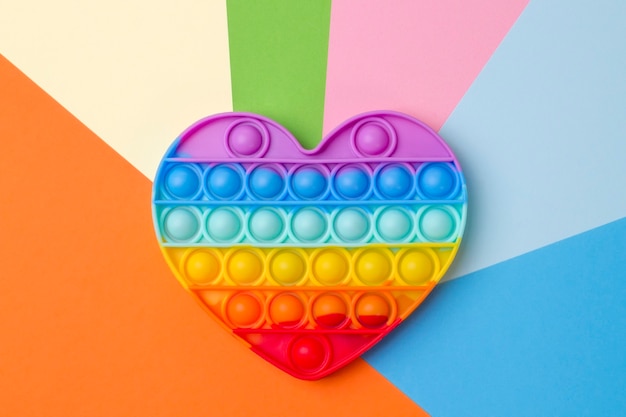 Jouet coeur arc-en-ciel en silicone sur fond multicolore coloré