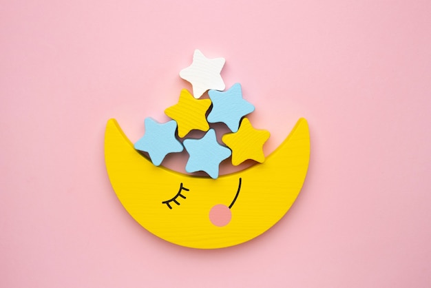 Jouet de développement pour enfants pour le développement de la motricité, un croissant de lune avec balancier d'étoiles, sur une vue de dessus de fond rose