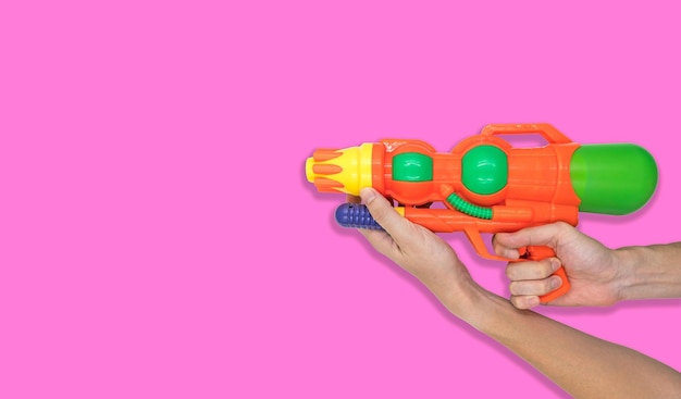 Jouet à l'eau avec pistolet à la main sur fond rose Espace libre pour le texte
