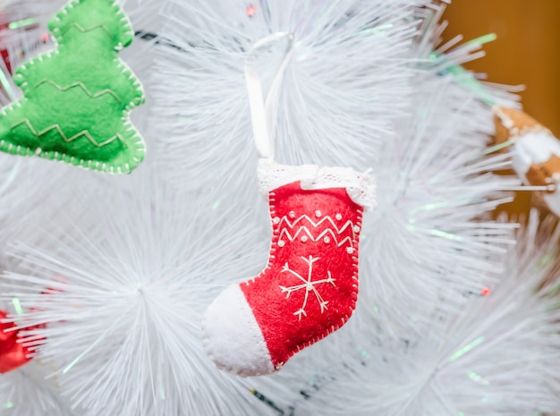 Jouet fait main sous la forme d'une chaussette accrochée à un arbre de Noël blanc.