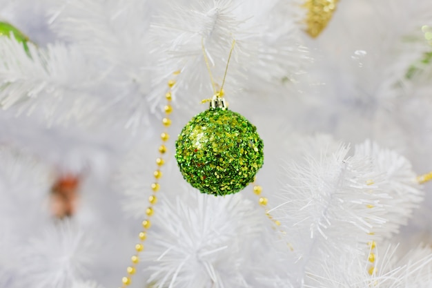 Jouet de Noël en plastique vert sur arbre de Noël blanc artificiel