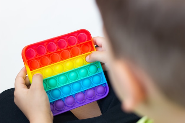 Jouet sensoriel anti-stress en silicone coloré pop-it dans les mains des enfants Jeu à la mode pour enfants et adultes