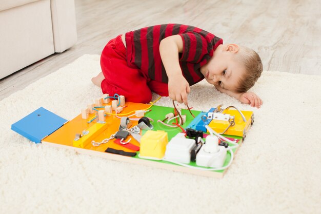 Jouet sensoriel pour enfants bricolage fait à la main, un garçon de trois ans joue avec une planche occupée