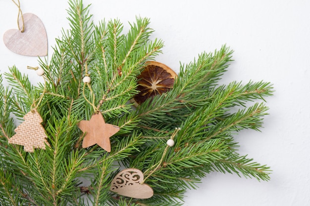 Jouets d'arbre de Noël et branches d'épinette naturelles sur fond blanc vue de dessus copie place, jouets d'arbre de Noël écologiques faits maison sur des branches d'épinette fraîches