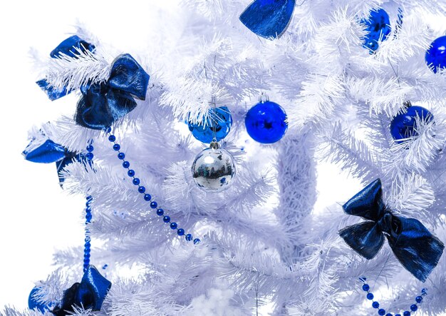 Les jouets bleus sont accrochés à un arbre de Noël blanc.