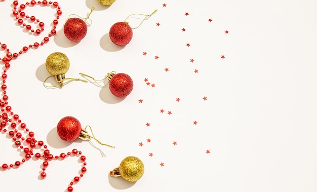 Jouets décoratifs de Noël de couleur rouge et or avec des perles rouges pour la décoration et des étoiles sur fond blanc. Espace pour l'espace de copie, pose à plat. Concept de vacances. Vue d'en-haut