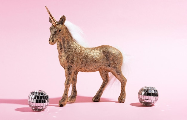 Des jouets de licorne dorés et des boules de disco sur fond rose Idée de carte de vacances