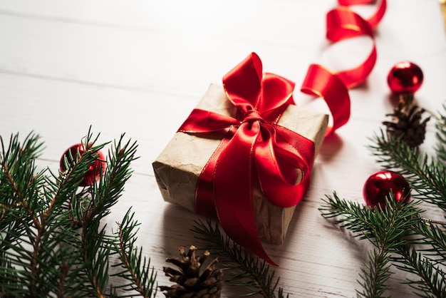 Jouets de Noël cônes de pin un cadeau avec un ruban rouge branches d'épinette sur une table en bois blanc 1