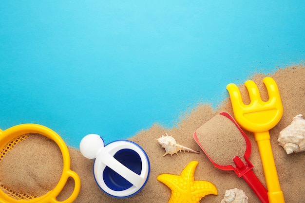 Jouets de plage d'été avec accessoires sur fond bleu avec espace de copie. Cadre d'été