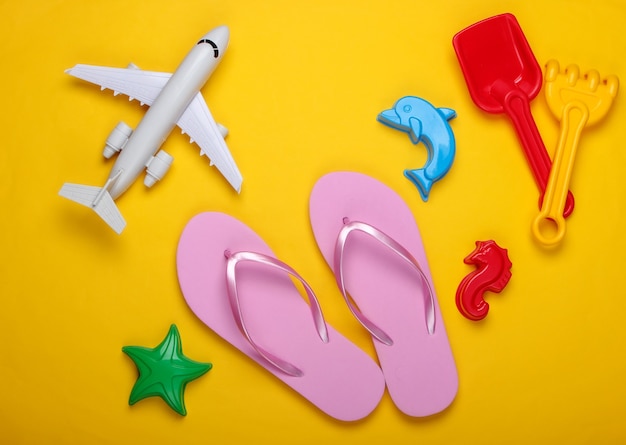 Jouets de plage pour enfants, tongs, avion sur un jaune