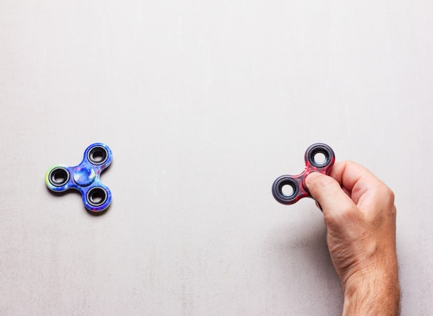 Jouets populaires à la main spinner en main masculine sur fond gris avec un espace pour le texte.