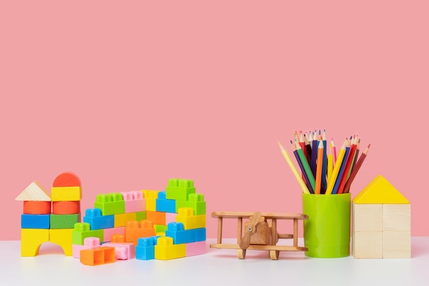 Jouets pour enfants sur fond rose Cubes en bois et un modèle d'avion crayons et un kit de construction en plastique