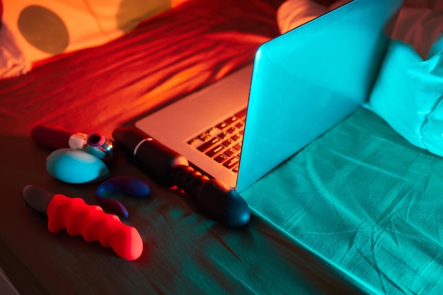 Photo jouets pour le sexe sur un ordinateur portable sur un fond néon lumineux