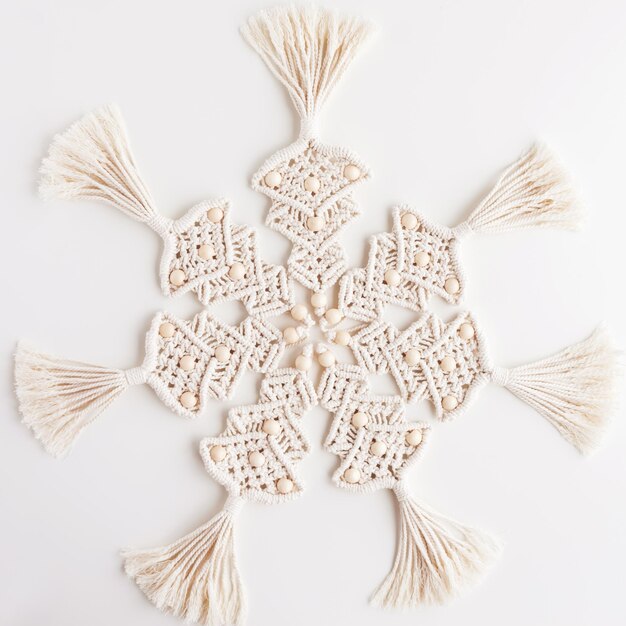 Jouets de sapin de Noël en macramé sur papier artisanal Fond blanc Matériaux naturels