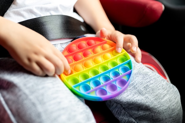 Jouets sensoriels anti-stress dans les mains des enfants. un petit garçon heureux joue avec un simple jouet à fossettes dans la voiture.