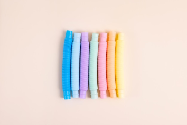 Jouets tendance pour enfants poptube coloré pastel sur fond beige ensemble de formes et de couleurs tube ondulé...