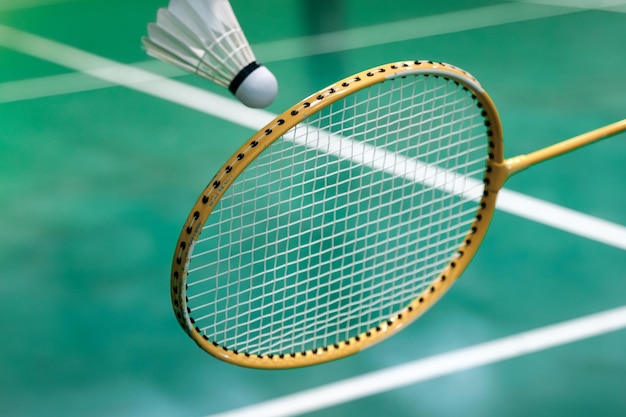 Le joueur de badminton tient un volant de badminton blanc et une raquette de badminton avant de le servir sur le net