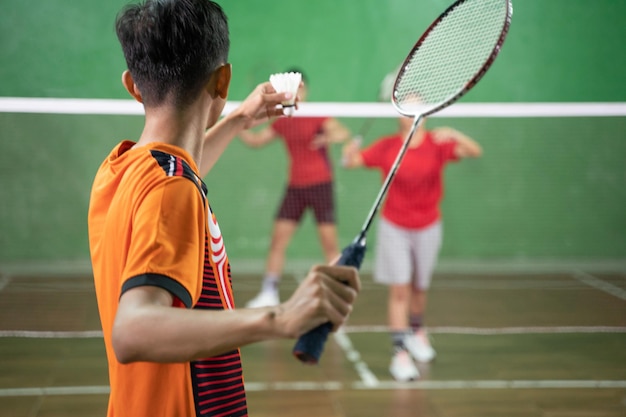 Photo joueur de badminton en uniforme orange prêt à servir