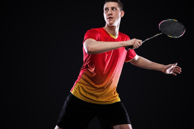 Joueur de badminton en vêtements de sport avec raquette et volant sur fond noir Sports individuels Loisirs sportifs