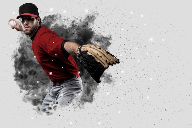 Joueur de baseball lanceur avec un uniforme rouge sortant d'une explosion de fumée.