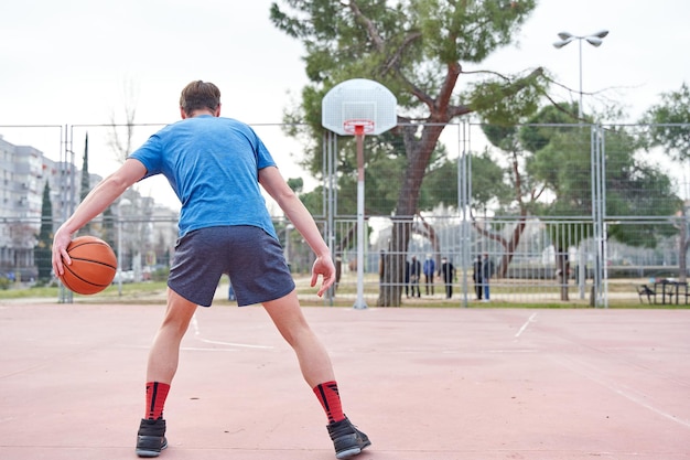 Joueur de basket-ball dribblant le ballon avant de tirer le panier jeune homme avec le ballon