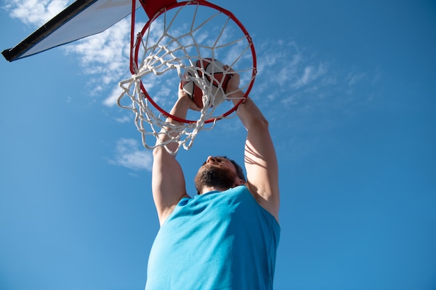 Joueur de basket-ball faisant un saut sur fond de ciel bleu