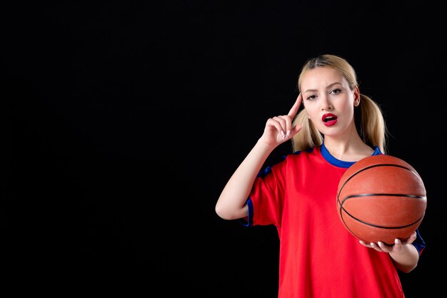 Joueur de basket-ball féminin avec ballon sur fond noir isolé athlète jouer à l'action de jeu