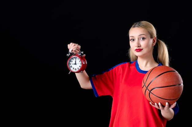 joueur de basket-ball féminin avec ballon et horloges sur fond noir athlète jouer à l'action de jeu