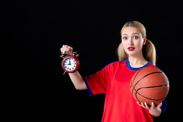 joueur de basket-ball féminin avec ballon et horloges sur fond noir athlète jouer à des jeux d'action