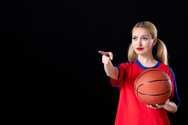 joueur de basket-ball féminin avec ballon pointant sur quelque chose sur fond noir jeu d'athlète de jeu