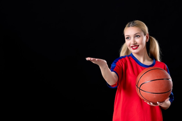 joueur de basket-ball féminin avec ballon pointant sur quelque chose sur fond noir jeu athlètes