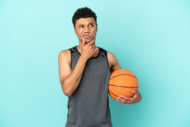 Joueur de basket-ball homme afro-américain isolé sur fond bleu ayant des doutes