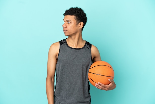 Joueur de basket-ball homme afro-américain isolé sur fond bleu regardant sur le côté