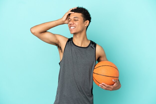 Joueur de basket-ball homme afro-américain isolé sur fond bleu souriant beaucoup