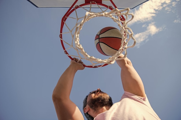 Le joueur de basket-ball lance la balle dans le ciblage extérieur cerceau