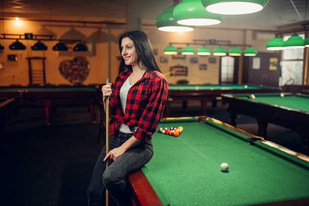 Joueur de billard féminin avec queue pose à la table