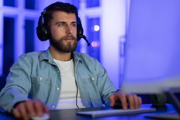 Joueur concentré avec un ordinateur la nuit à la lumière du néon