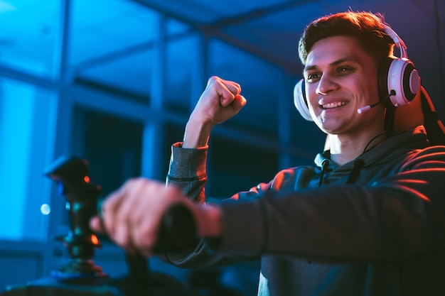 Le joueur avec des écouteurs assis et jouant à des jeux vidéo dans la salle au néon