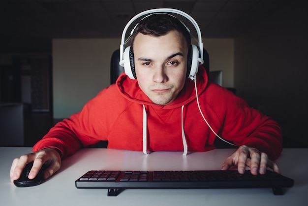 Joueur endormi jouant à des jeux vidéo à la maison sur l'ordinateur. Jeune homme avec un casque près de l'ordinateur.