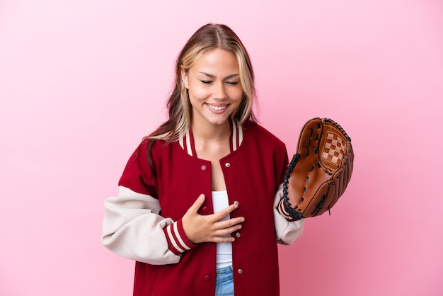 Joueur femme russe avec gant de baseball isolé sur fond rose souriant beaucoup