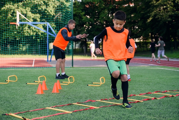 Joueur de football adolescent exécutant des exercices d'échelle sur le gazon pendant la formation de football