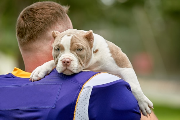 Joueur de football américain avec un chien qui pose en caméra dans un parc. fond, bannière de sport. football américain, sport la protection des animaux.