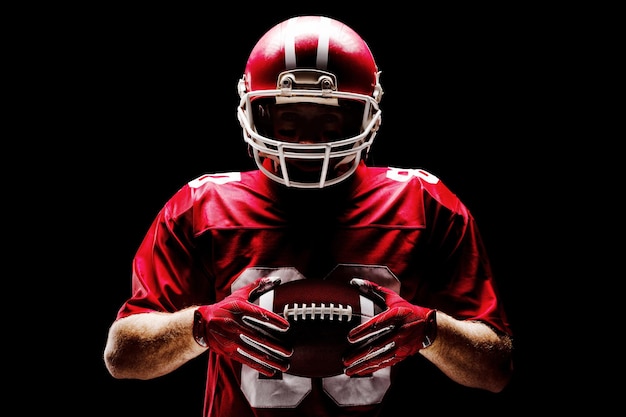 Joueur de football américain debout avec un casque de rugby et un ballon