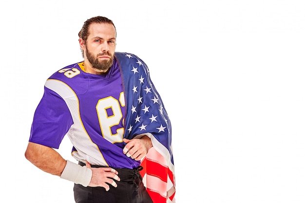 Joueur de football américain patriotique se présentant à la caméra sur fond blanc avec drapeau usa. Le concept de patriotisme, appel à l'action, bannière sportive du football américain.