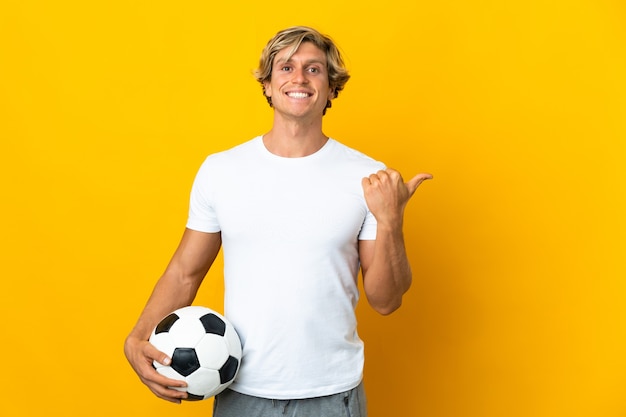 Joueur de football anglais sur fond jaune isolé pointant vers le côté pour présenter un produit