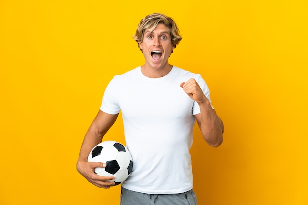 Joueur de football anglais sur mur jaune isolé célébrant une victoire en position de vainqueur