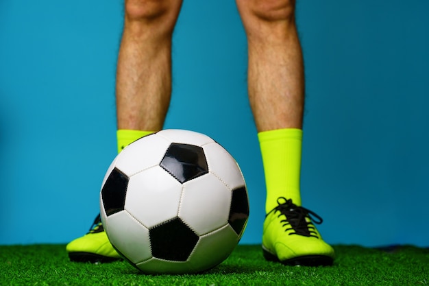 Photo joueur de football avec ballon sur l'herbe verte et bleue